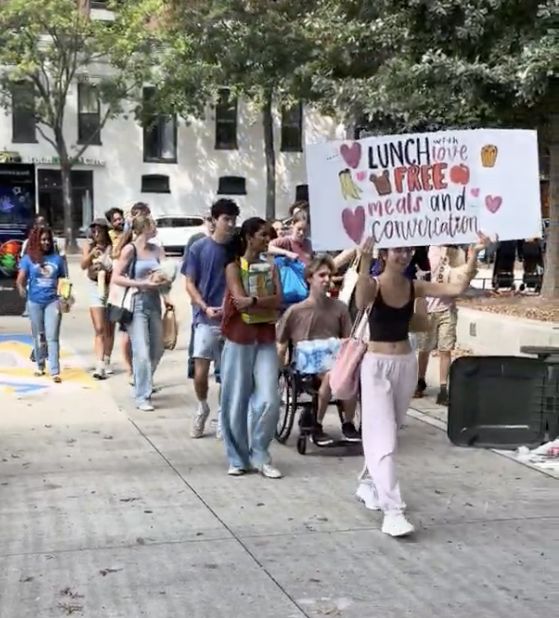 The group walking with the Lunch With Love sign