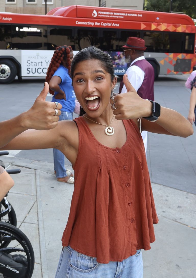 A volunteer giving two thumbs up downtown